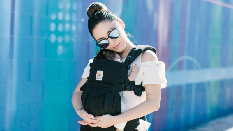 Woman carries newborn in Ergobaby Omni 360 baby carrier in black