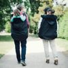 action shot of two parent wearing bundlebean rain covers to keep baby and toddler dry and warm