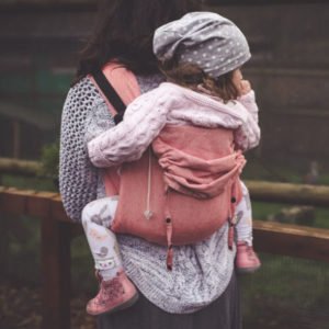 Woman carries child on her back in Didymos DidyGo Onbuhimo baby carrier in Chilli