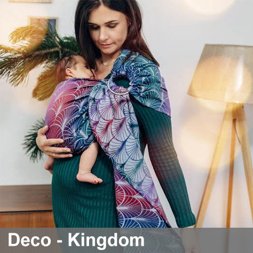 Woman carries baby on her front in Lenny Lamb Ring Sling in Deco Kingdom fabric