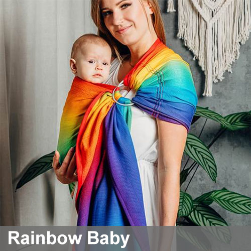 Woman carries baby on her front in Lenny Lamb Ring Sling in Rainbow Baby fabric