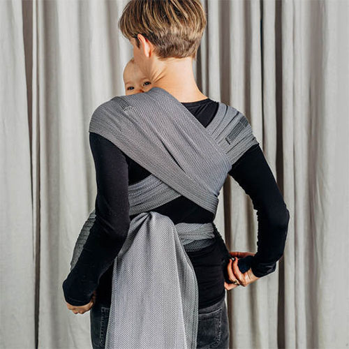 Back view of woman carrying baby in Lenny Lamb Wrap Tai baby carrier in Little Herringbone Ombre Grey fabric