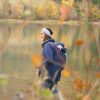 Woman carries baby on her back while wearing the Mamalila Cosy Allrounder babywearing coat in Navy