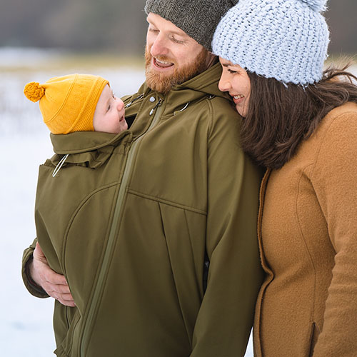 Man carries baby in carrier while wearing the Mamalila Mens Softshell Allrounder babywearing jacket in khaki