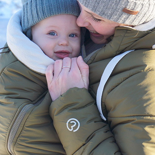 Close up of woman carrying baby in carrier wearing the Mamalila Copenhagen babywearing coat over the top of them both